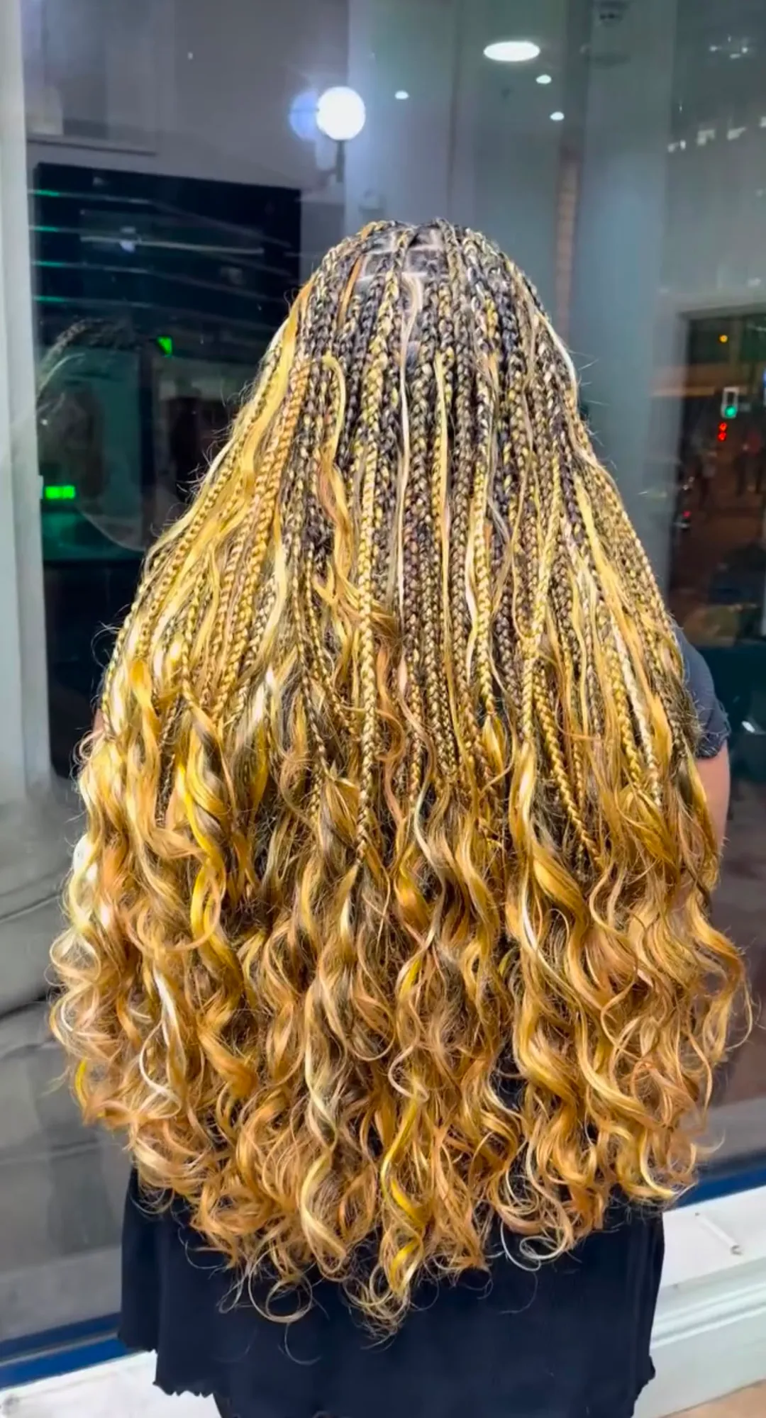 Honey-blonde boho knotless braids with curly ends, back view
